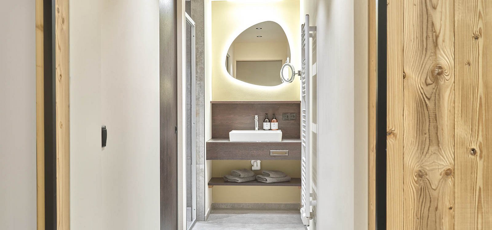 Heller Badflur mit Spiegel, Waschbecken und Handtüchern unter der Ablage