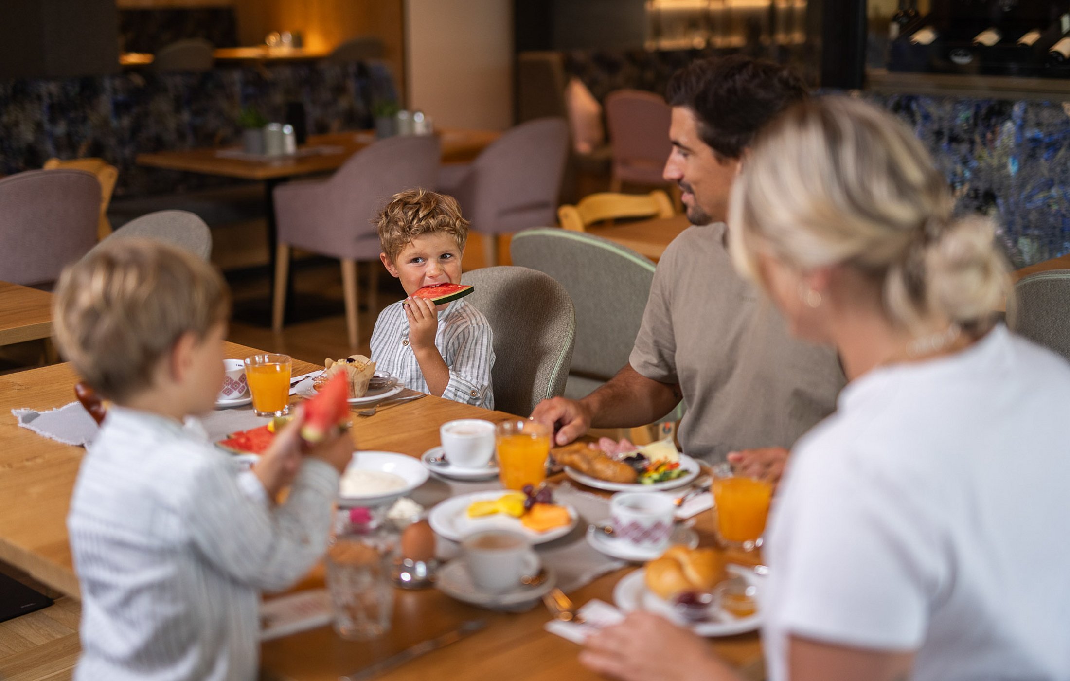 Eine vierköpfige Familie sitzt gemeinsam am reich gedeckten Frühstückstisch im Hotelrestaurant