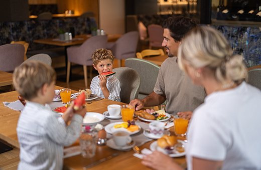 A family of four sitting together at a set breakfast table in the hotel restaurant