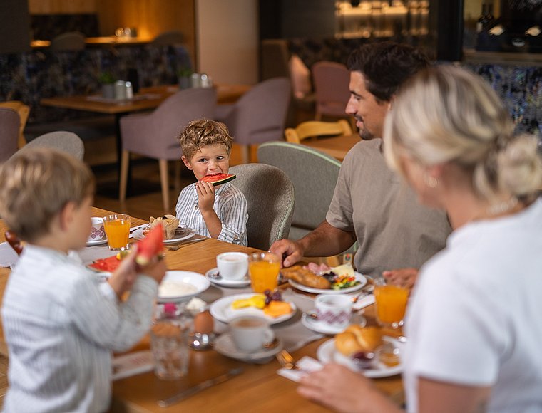 A family of four sitting together at a set breakfast table in the hotel restaurant