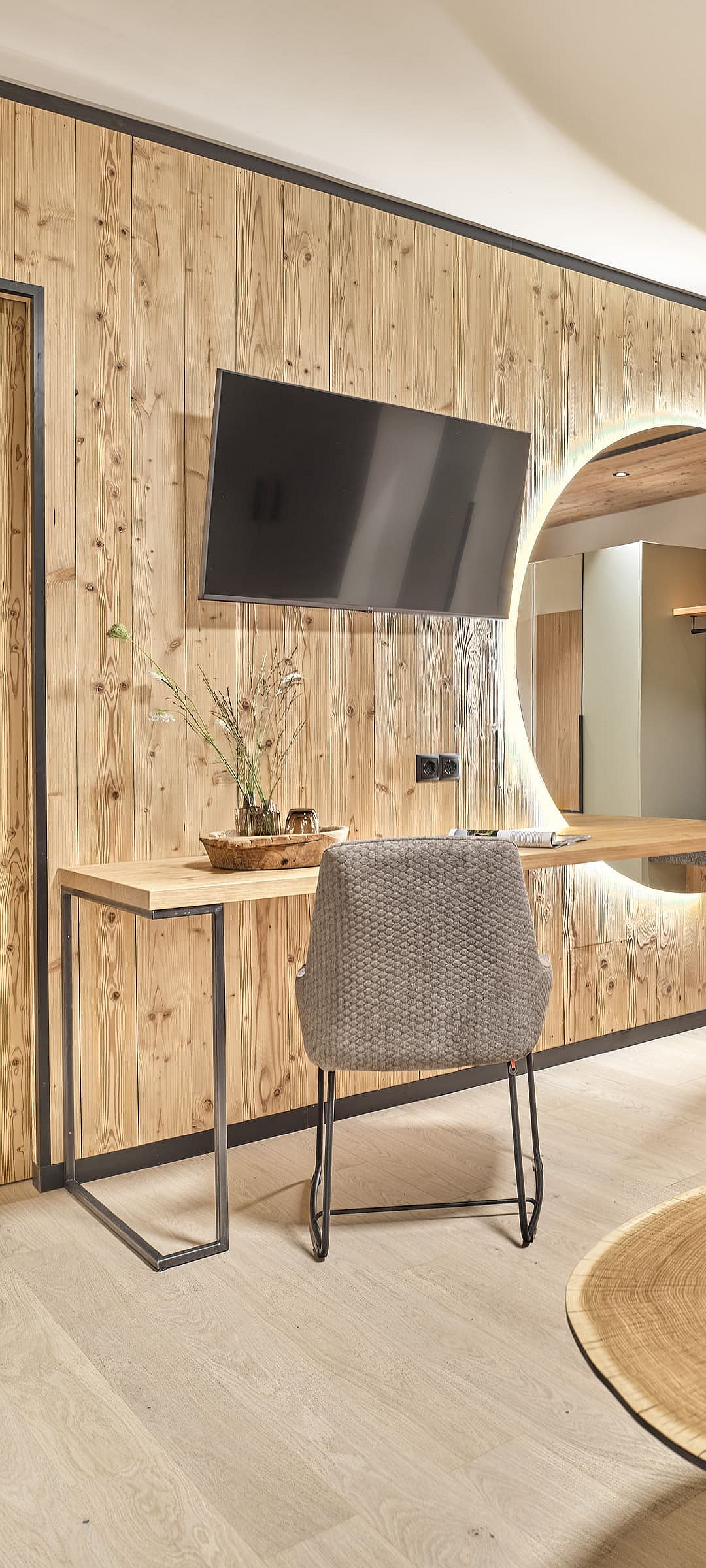 Schreibtisch mit Fernseher und großem Wandspiegel im modernen Hotelzimmer