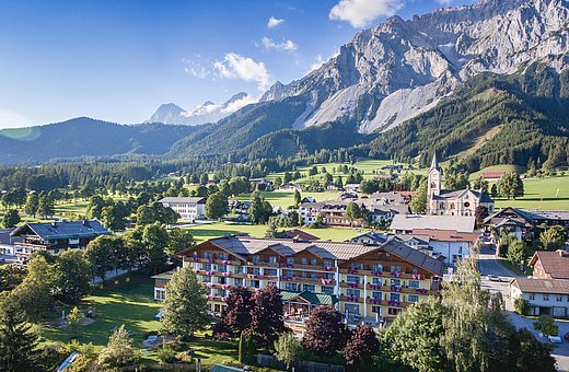 Panorama mit Hotel Matschner und Kirche in der grünen Landschaft vor Felsmassiv
