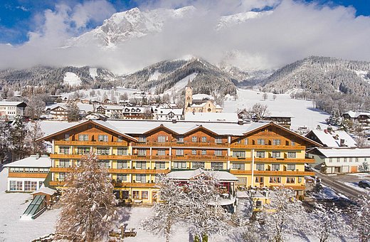 Front view of snowy Hotel Matschner with mountains and church in the background