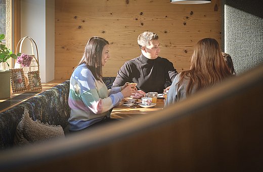 Family enjoying breakfast together in a rustic wooden booth in the bright hotel restaurant